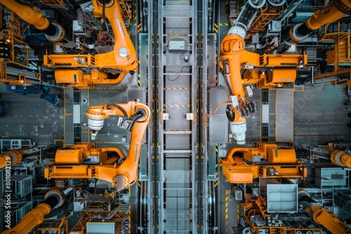 Overhead view of robotic arms in synchronized motion in an automotive factory assembly line