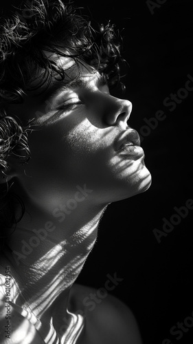retrato de perfil de una persona joven, capturado entre sombras, que transmite una sensación de misterio y profundidad.  photo