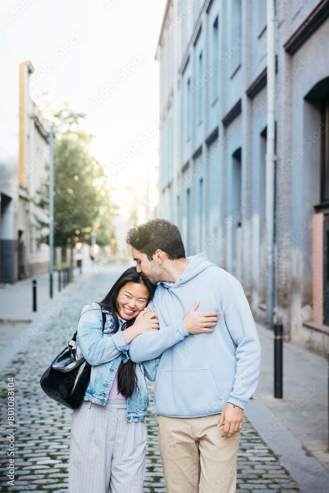 Interracial couple walking on a sidewalk holding hands. Young man and woman walking on city street. Interracial couple walking on a sidewalk holding hands. Young man and woman walking on city street.