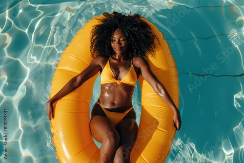 black woman relaxing in inflatable pool ring dinghy lilo, with rippling swimming pool water photo