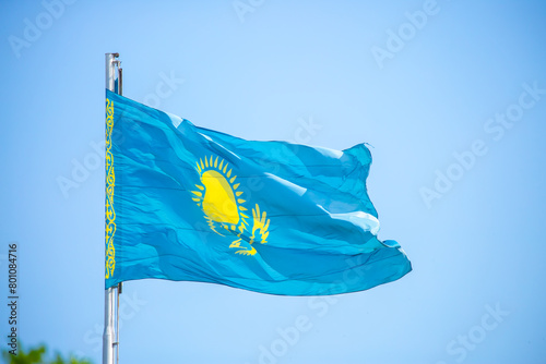 The flag of Kazakhstan is fluttering in the wind against the blue sky. The flag is located on the blue dome of the administrative building. The city of Astana is the administrative center.