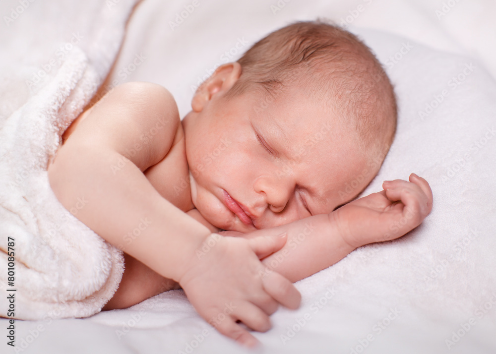 A newborn baby peacefully sleeping on a soft white blanket A newborn baby peacefully sleeping on a soft white blanket