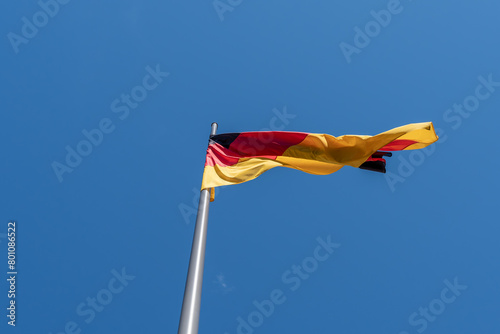 Waving German flag against a blue sky. German flag on the roof of a building. photo