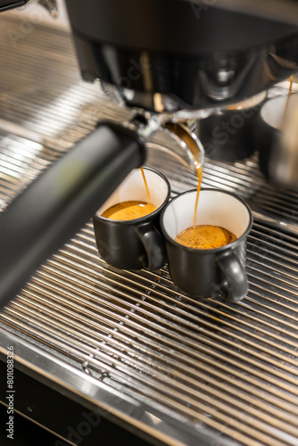 Espresso machine pouring fresh coffee into two black cups