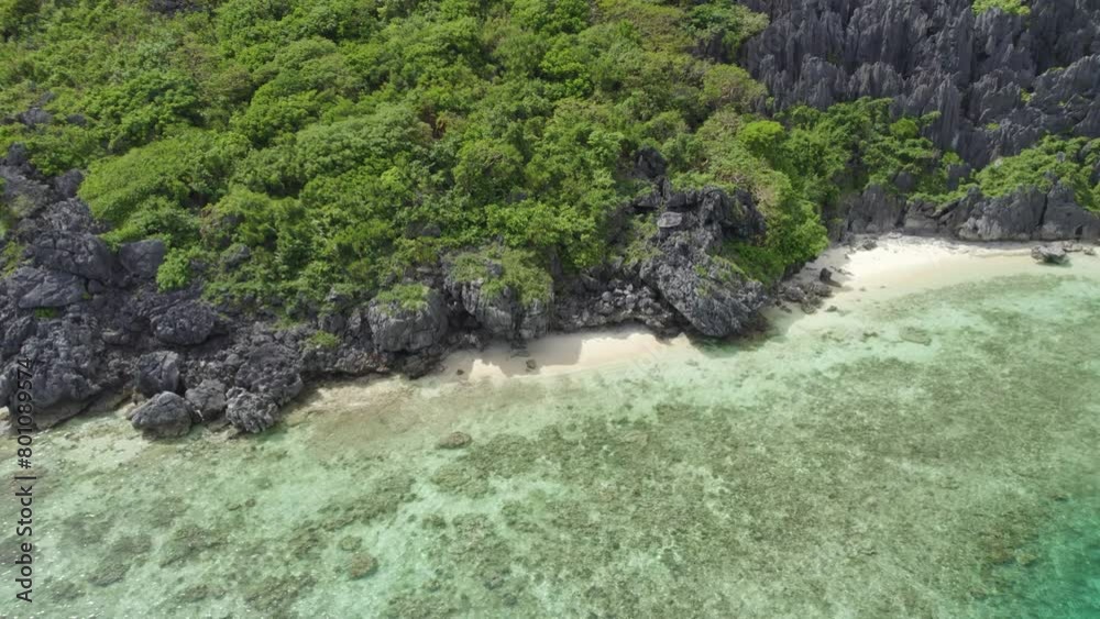 Philippines. A rocky shoreline with a lush green hillside in the background. The water is calm and clear, and the sky is blue. Philippines. A rocky shoreline with a lush green hillside in the background. The water is calm and clear, and the sky is blue.