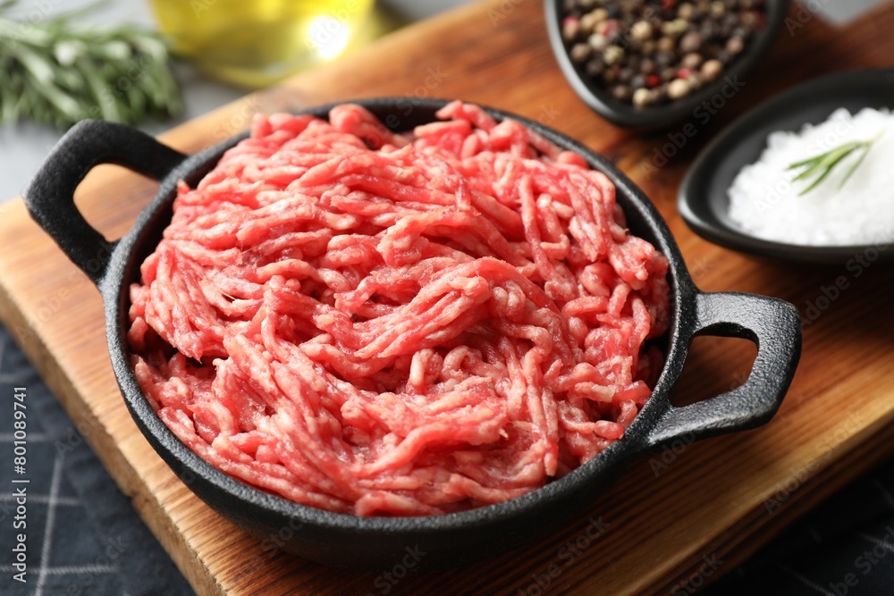 Raw ground meat in bowl and spices on table, closeup