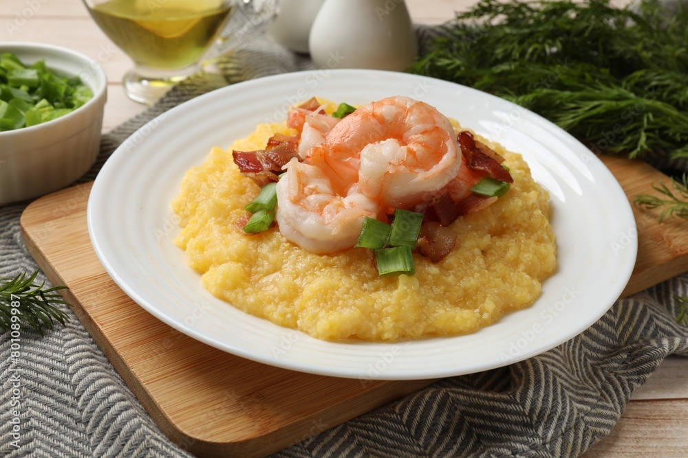 Plate with fresh tasty shrimps, bacon, grits and green onion on wooden table