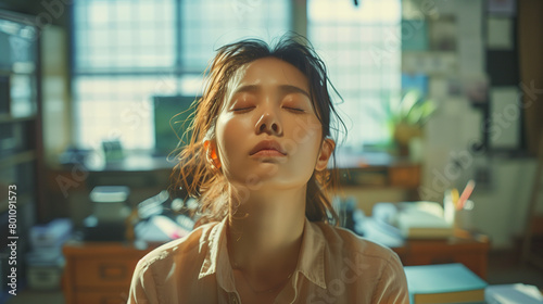Symbolizing vulnerability  an Asian female employee feels tired and dizzy while working in the office  highlighting the strain of her workload.