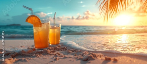 Orange cocktails on beach sand with a sunset and palm leaves in the background, warm tones with copyspace for text on the right.