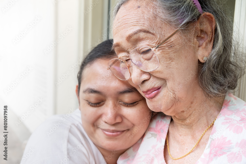 A happy Asian mature adult daughter hugging her old mother when visiting her at home A happy Asian mature adult daughter hugging her old mother when visiting her at home