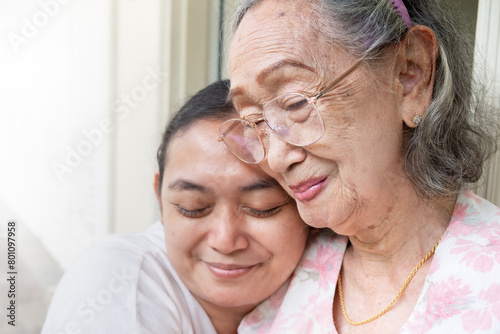 A happy Asian mature adult daughter hugging her old mother when visiting her at home