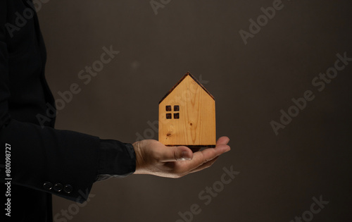Man hold the wood house in hand. The real estate investment. House sale, rental and leasing in long term investment. Insurance. Financial loan, mortgage loan.