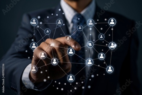 A man in a suit is pointing at a network of people on a computer screen