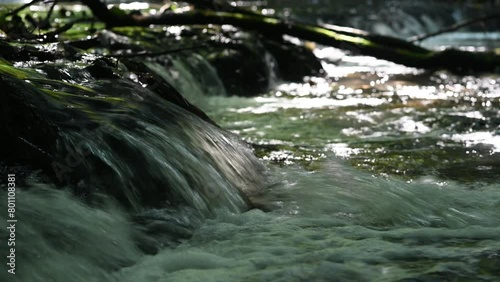 A roaring small waterfall on the river in the valley in the morning