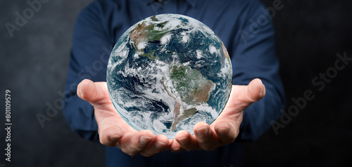 Fototapeta Naklejka Na Ścianę i Meble -  Man with the world with his hands on black background - elements of this image furnished by NASA.