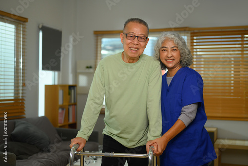 Friendly nurse assisting elderly man using walking frame. Rehabilitation and Healthcare concept
