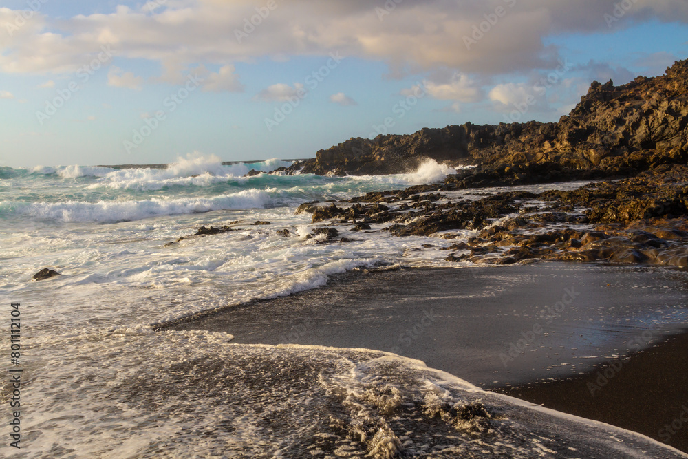 Black volcanic rocks on the Atlantic coast at sunset. Playa de las Malvas, Lanzarote, Canary Islands, Spain