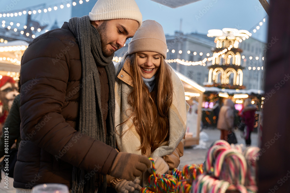 Caucasian couple buying candies on Christmas market at night