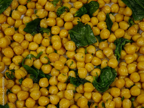 Fresh boiled chick-pea sprinkling with fresh parsley and spinach leaves, background