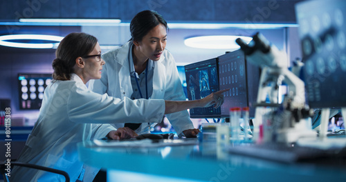 Fotografie Medical Hospital Research Laboratory: Caucasian And Asian Female Scientists Talking And Using Desktop Computer With CT Scans Of Human Brain