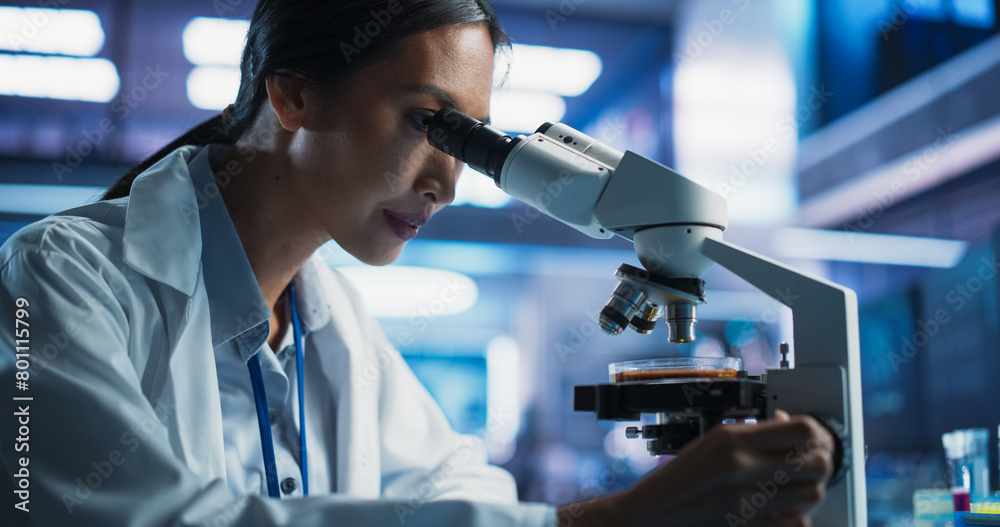 Medical Development Laboratory: Close-Up Portrait of Asian Female Scientist Using Microscope, Analyzes Petri Dish Sample. Big Pharmaceutical Lab doing Medicine, Biotechnology, And Drugs Research. Medical Development Laboratory: Close-Up Portrait of Asian Female Scientist Using Microscope, Analyzes Petri Dish Sample. Big Pharmaceutical Lab doing Medicine, Biotechnology, And Drugs Research.