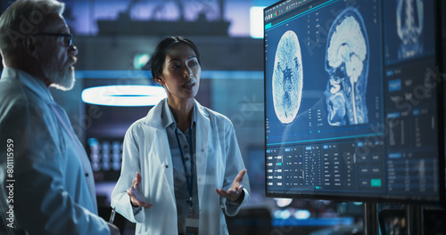 Tableau sur toile Neuroscience Laboratory Meeting: Female Asian Scientist And Male Caucasian Surgeon Discussing MRI Brain Scan On TV Display