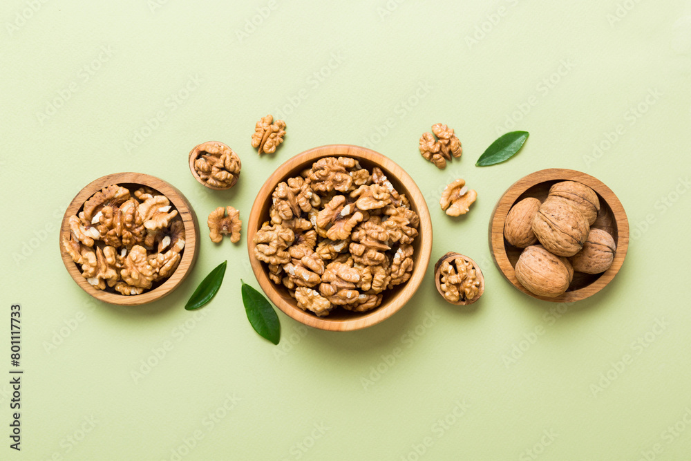 Fototapeta premium Walnut kernel halves, in a wooden bowl. Close-up, from above on colored background. Healthy eating Walnut concept. Super foods with copy space