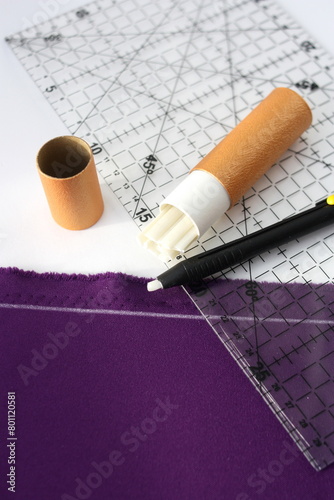 A set of tailor's chalks lies on the fabric. The concept is cutting and sewing clothes. Vertical photo.