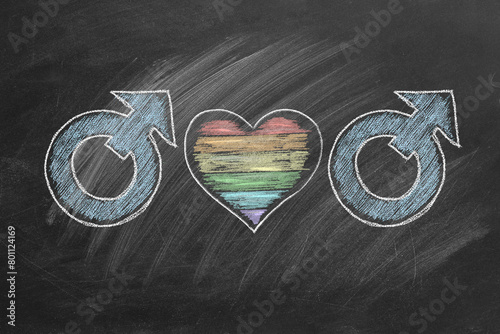 Gender symbols for male interconnected with a heart featuring rainbow colors drawn on a chalkboard. LGBT concept