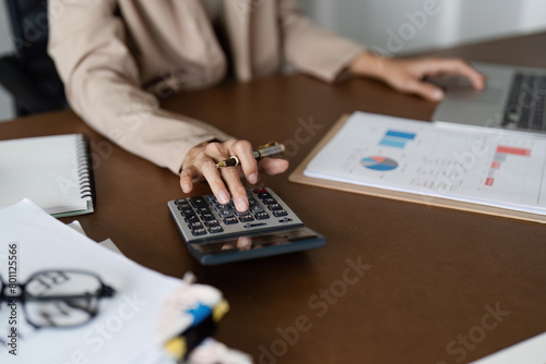 Businesswoman using a calculator to calculate numbers on a company's financial documents, she is analyzing historical financial data to plan how to grow the company. Financial concept photo