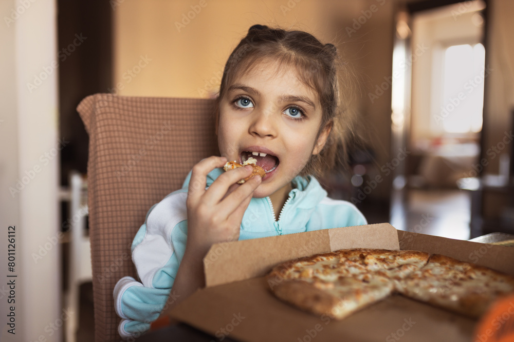 little girl eats pizza close up at home