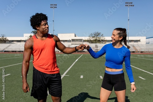 Male and female athletes fist bumping