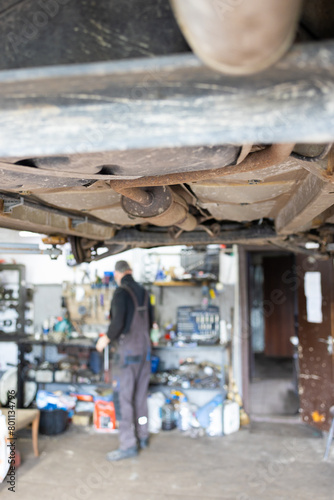 Auto mechanic repairing a car in auto repair shop, blurred background. © Mykola