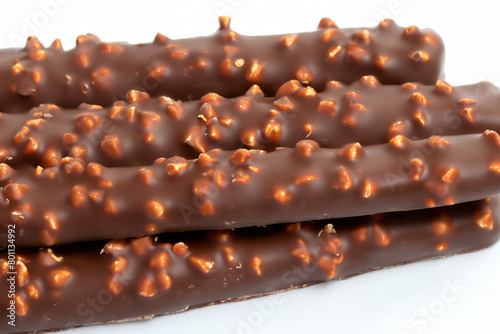 chocolate tubes. there is a stack of chocolate tubes with nuts on a white table, top view, close-up, sweet concept