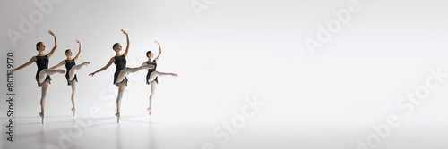 Four ballet dancers, teen girls in black leotards dancing against grey studio background. Synchronization. Ballet, art, dance studio, classical style, youth concept. Banner. Empty space to insert text photo