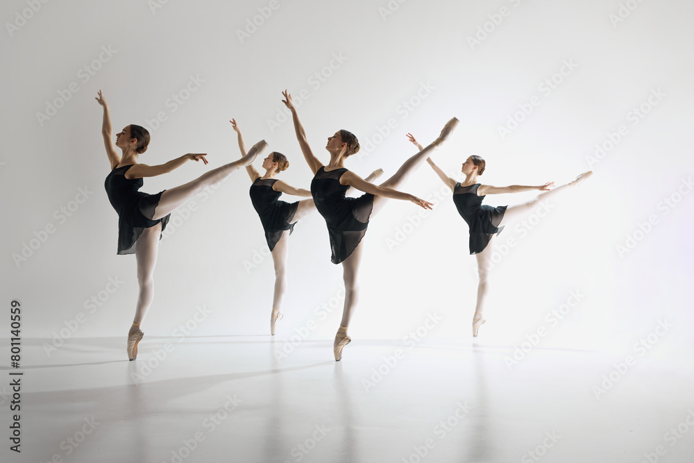 Inspiration. Young teen girls, graceful ballerinas in back costumes standing on pointe, training, performing complex ballet moves. Concept of ballet art, dance studio, classical style, youth
