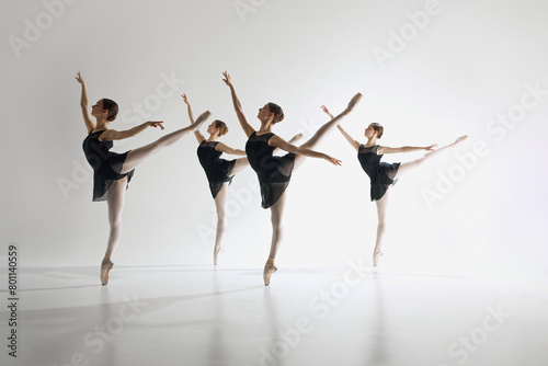 Inspiration. Young teen girls, graceful ballerinas in back costumes standing on pointe, training, performing complex ballet moves. Concept of ballet art, dance studio, classical style, youth © master1305