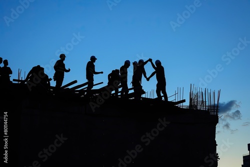 Two construction workers shake hands on top of a building under the sky