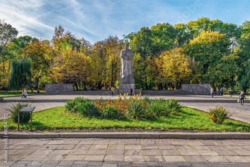 Lviv, Ukraine - November 2, 2023: Monument to Ivan Franko against the backdrop of the autumn Ivan Franko Park in Lviv. People walk along the square near the statue of the famous writer on a sunny day
