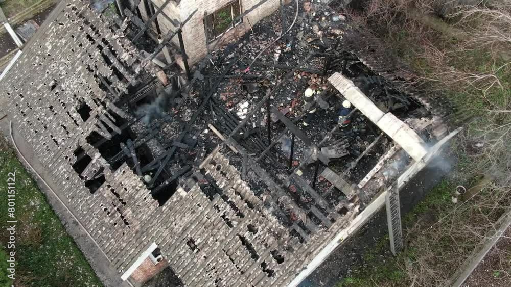 Top view of a burnt house. The house was completely destroyed by fire. The roof collapsed, the walls turned black. Burnt items are scattered around the house. Fire in a private house.