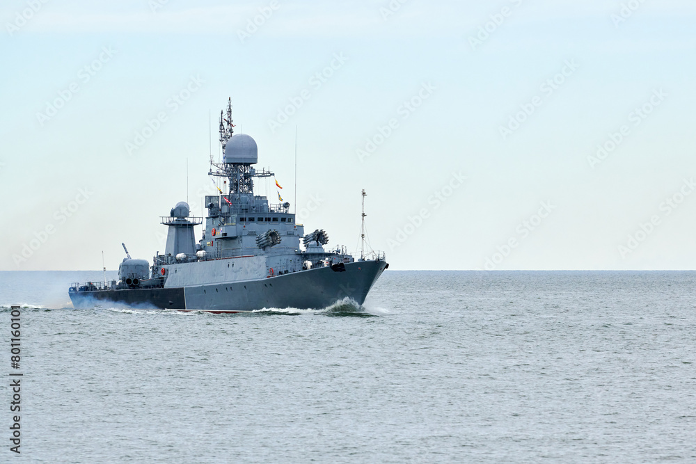 Russian warship armed with armament sails into sea toward military target to attack and destroy enemy, military ship performing strategic maneuver, Russian sea power deployment for tactical advantage