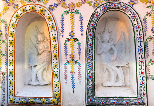 White bas-reliefs of Kinnara decorated with colorful floral ornament in a Wat Arun Buddhist temple at Bangkok, Thailand