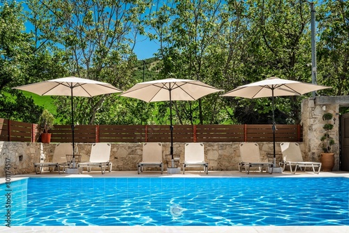 Swimming Pool Area with Sunbeds and Open Umbrellas  Perfect for Relaxation on a Bright Sunny Day.  Suitable for advertising or promoting vacation resorts  luxury hotels  or leisure destinations.