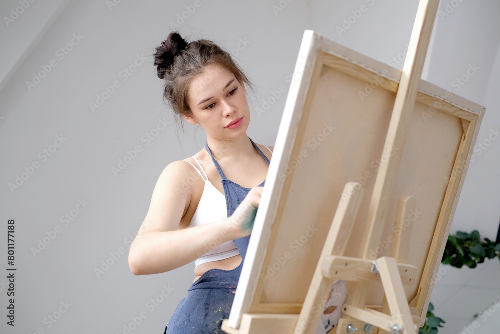 Young female artist paints a picture with oil on canvas in art studio Young female artist paints a picture with oil on canvas in art studio