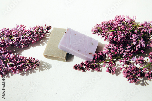 A bar of natural soap with lilac flowers on a concrete background. Cosmetics from natural ingredients, herb. Top view