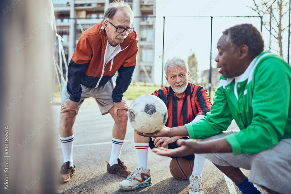 Senior friends playing soccer together in urban park Senior friends playing soccer together in urban park
