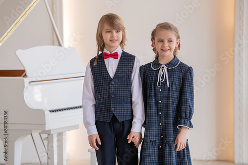 Two children are singing in front of a piano .