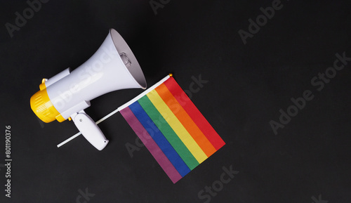  Rainbow pride flag and megaphone on black background.