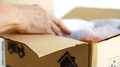 宅配便のダンボール箱に包装した荷物を入れる高齢の女性 photo