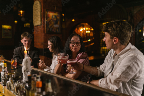 Man and woman cheers glasses with beverages celebrating meet in bar. Happy guests clink alcohol drinks sitting at pub counter